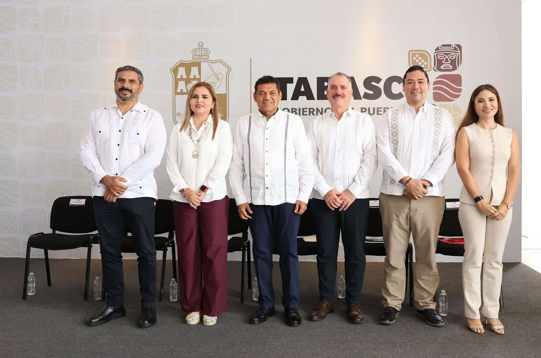 Transformación En La Salud Y Agenda De Trabajo: Claves De La Conferencia De Prensa Del Gobernador Javier May Rodríguez 72 Una Fotografía De Grupo Con Seis Funcionarios De Tabasco De Pie Frente A Una Pared Con El Logo Del Gobierno Estatal. De Izquierda A Derecha: Cuatro Hombres Con Guayaberas Blancas Tradicionales Y Pantalones Oscuros O Caqui, Una Mujer Con Blusa Blanca Y Pantalones Color Vino, Y Una Mujer Con Un Conjunto Beige Sin Mangas. Sonríen A La Cámara.