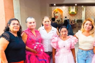 Tres Mujeres De La Tercera Edad Luciendo Vestidos De Quinceañera En Tonos Rosa Y Fucsia Posan Sonrientes Junto A Acompañantes A Las Afueras De Una Iglesia En Villahermosa, Tabasco.