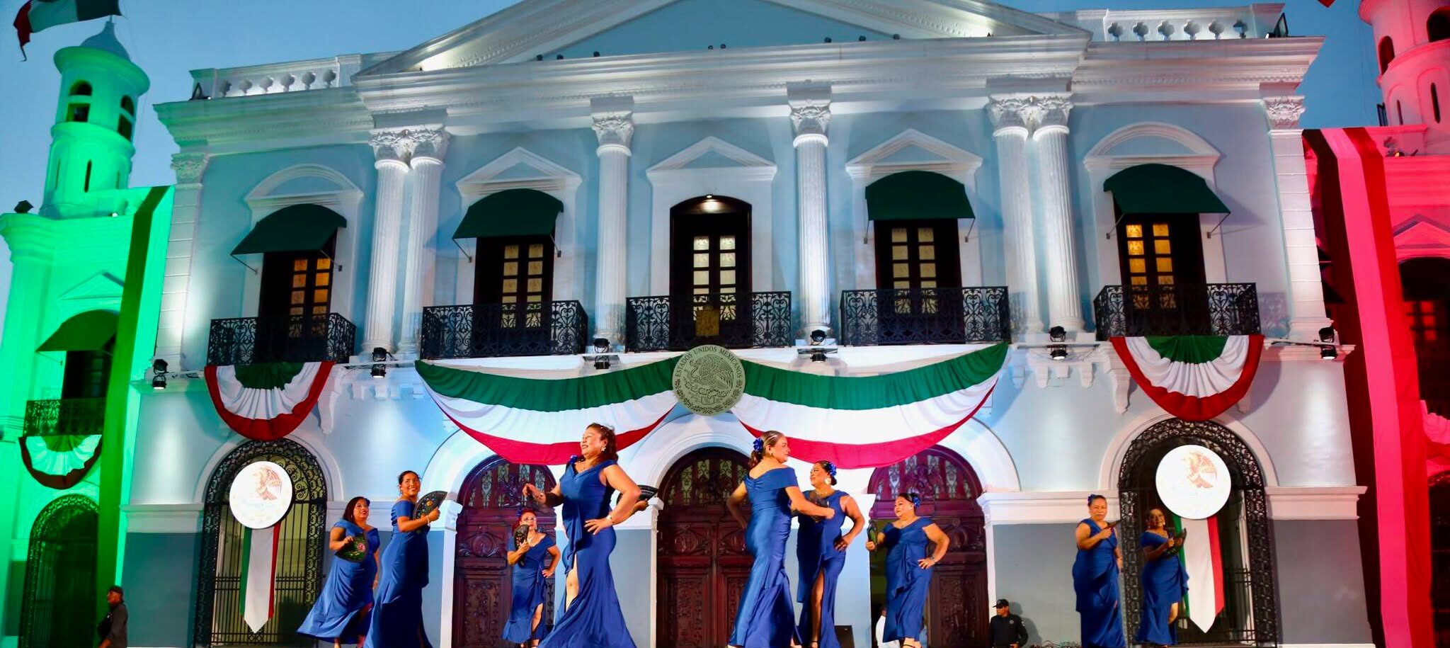 Ballet Folclórico Con Vestidos Azules Bailando En Un Escenario Frente A Un Edificio Gubernamental Decorado Con Motivos Patrios Durante La &Amp;Quot;Fiesta Mexicana En El Edén&Amp;Quot; En Tabasco.