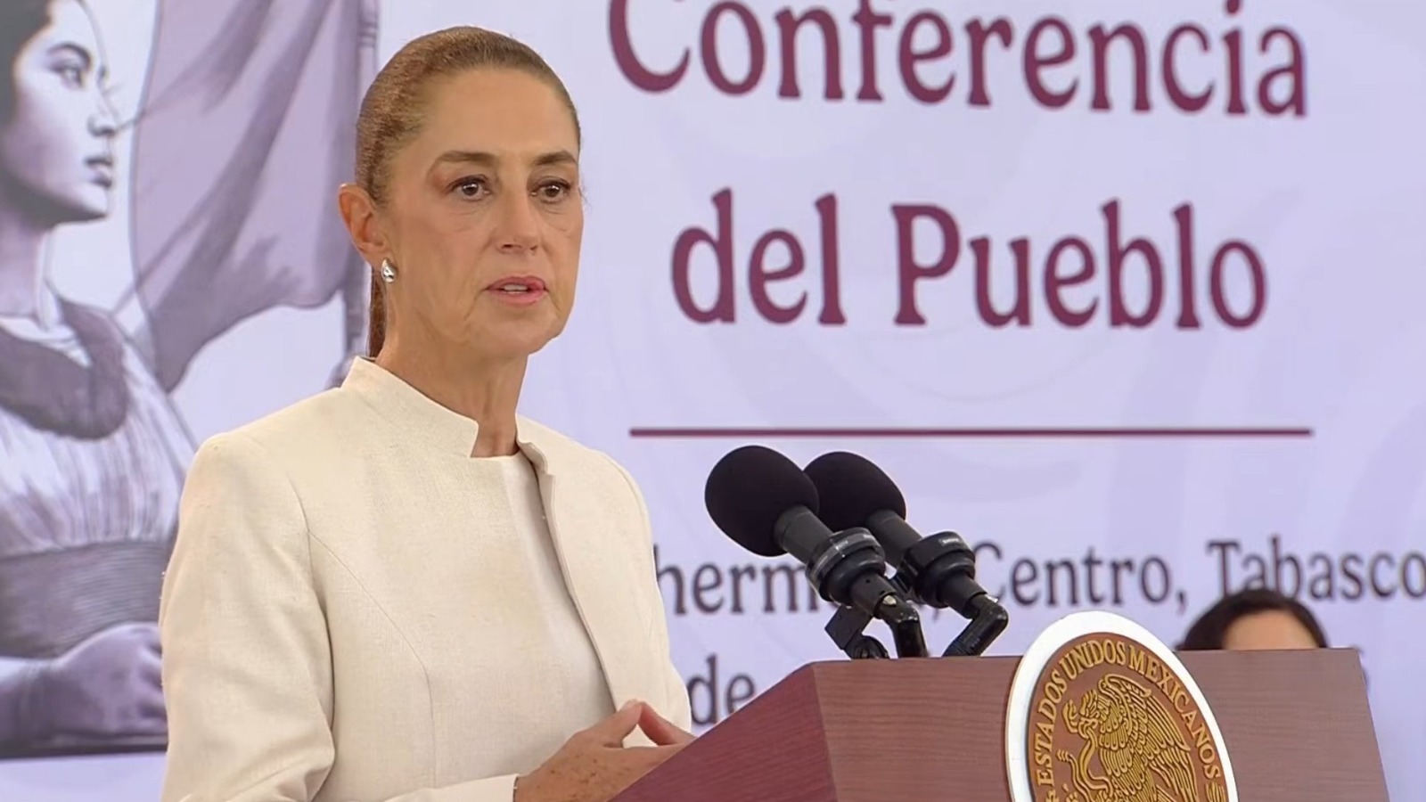 Gira Presidencial En Tabasco: Claudia Sheinbaum Encabeza Mesa De Seguridad Y Presenta Avances Estratégicos En Educación, Campo Y Turismo La Presidenta De México, Claudia Sheinbaum Pardo, Durante Una Conferencia De Prensa Desde Villahermosa, Tabasco, Vistiendo Un Saco Beige Y Hablando Frente A Micrófonos Y El Escudo Nacional.