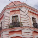 Fachada De Un Edificio Histórico De Dos Pisos En Tonos Salmón Y Blanco Con Balcones De Herrería Negra, Ubicado En Una Esquina Del Centro Histórico De Villahermosa.