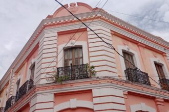 Fachada De Un Edificio Histórico De Dos Pisos En Tonos Salmón Y Blanco Con Balcones De Herrería Negra, Ubicado En Una Esquina Del Centro Histórico De Villahermosa.