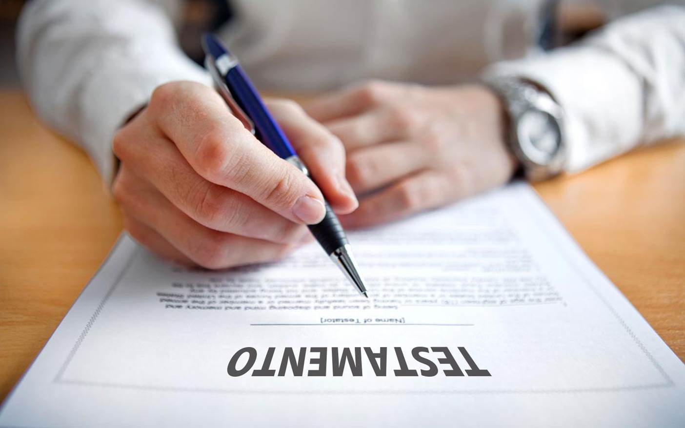 Primer Plano De Una Persona Sosteniendo Un Bolígrafo Azul A Punto De Firmar Un Documento Legal Que Lleva El Título &Quot;Testamento&Quot; En Letras Mayúsculas Sobre Un Escritorio De Madera.