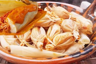 Plato De Barro Con Chanchamitos Envueltos En Hojas De Maíz Y Un Detalle Superior Mostrando Uno Abierto Con Salsa.