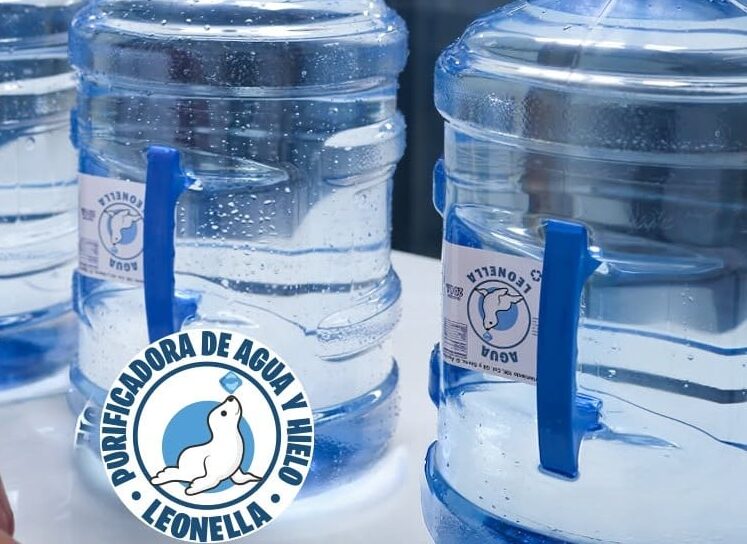 Seguridad Y Confianza En Cada Gota:¿Por Qué La Certificación Es Clave En Leonella Purificadora De Agua? Garrafones Azules De Leonella Purificadora De Agua Alineados En Una Mesa Mientras Una Persona De Blusa Roja Se Acerca A Manipularlos