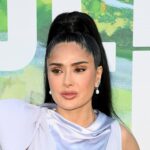 Salma Hayek Luciendo Un Vestido Satinado De Color Lavanda Con Un Lazo Estrucutrado En El Hombro Y Una Coleta Alta Tirante Durante Un Evento De Alfombra Roja.